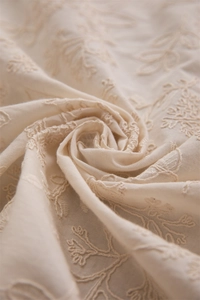 Detailed macro view of French embroidered cotton tablecloth with elegant floral patterns