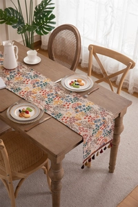 Detailed view of jacquard table runner with vintage floral patterns and fringe tassels