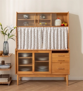 Detail of a wooden sideboard featuring fluted glass doors and floral fabric curtain