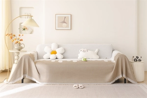 Detail of chenille sofa cover showing wavy edge, white tassels, and jacquard texture