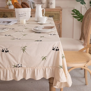 Detailed embroidery of panda and bamboo on beige ruffled cotton tablecloth corner