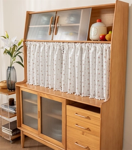 Detail of solid wood sideboard featuring fluted glass doors and a floral print curtain