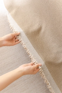 Close-up of Nordic chenille sofa cover showing jacquard weave and cream fringe details