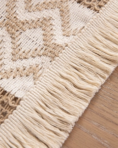Close-up of woven cotton linen table runner featuring cream stripes and handmade tassels