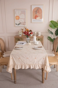 Detail of apricot cotton tablecloth with orange butterfly embroidery and ruffle edges