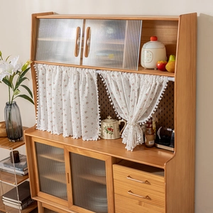 Detail of a floral cotton curtain on a wooden kitchen cabinet with fluted glass doors