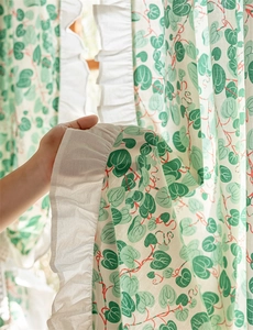 Close-up of cotton floral curtain featuring green heart leaves and white ruffled edges