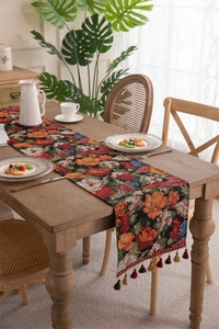 Macro view of floral jacquard table runner with decorative fringe on dark wood table
