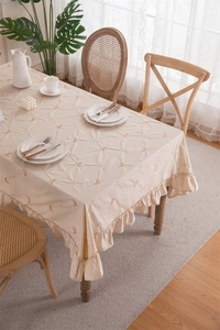 Detailed view of apricot cotton tablecloth with embroidered butterflies and ruffled edges
