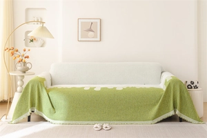 Detail of chenille sofa throw with grass green wavy edges and decorative tassels
