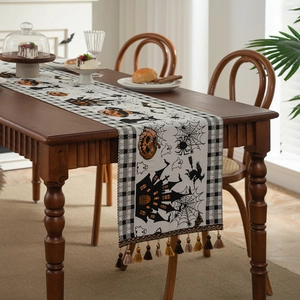 Halloween table runner with pumpkins and ghosts featuring checkered edges and tassels