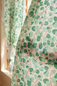 Close-up of cotton floral curtain featuring green heart leaves and ruffled edge details