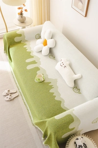 Close-up of Nordic chenille sofa cover with green cat paw prints and tassel fringe edges