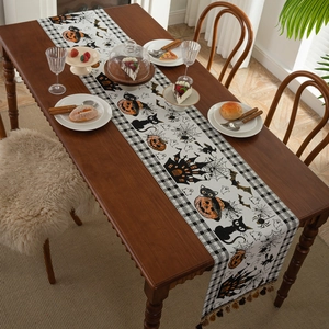 Halloween table runner with pumpkins and bats on wooden table with tassels