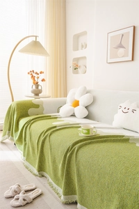 Close-up of green chenille sofa throw cover with textured jacquard and tassel details