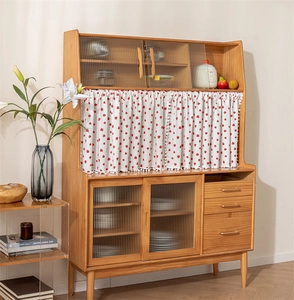 Detail of cotton printed short curtain on a wooden kitchen cabinet with tassel trim