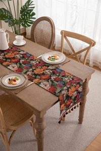Macro detail of American vintage floral table runner with colorful fringe on wood table