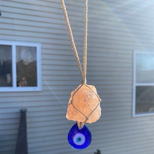 Bohemian orange crystal stone pendant with evil eye charm in natural sunlight