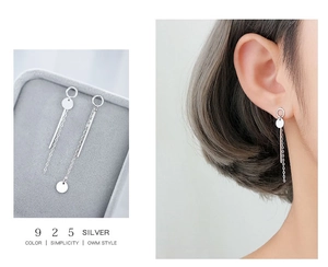 Detail of S925 sterling silver asymmetric drop earrings with disc and chain tassel on model