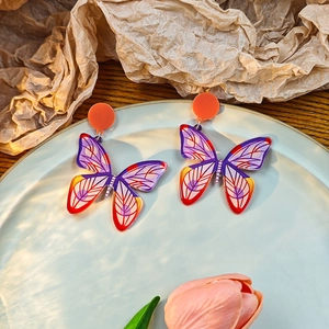 Detailed close-up of butterfly earrings with artistic oil painting patterns and floral decor