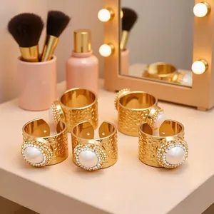 Set of five gold adjustable rings with natural pearls and rhinestones on a vanity desk
