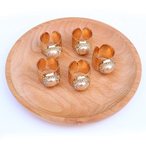 Close-up of five adjustable gold-plated pearl rings with rhinestones on a wooden tray