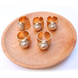 Detailed view of five adjustable gold rings with hammered texture and pearl inlay
