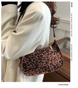 Dettaglio della borsa baguette leopardata con fibbie dorate su un cappotto bianco