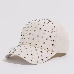 Detail showing high-quality silver metal studs and rivets on cream baseball cap