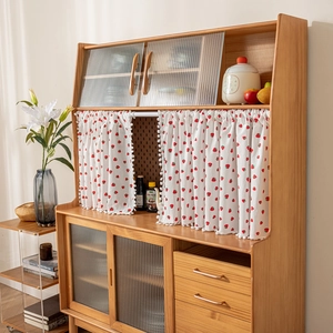 Detail of strawberry print cabinet curtain with decorative white pom-pom fringe trim