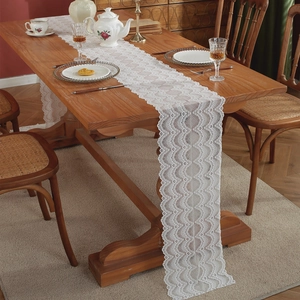 Eleganter weißer französischer Spitze-Tischläufer mit Blumenmuster auf einem Holztisch
