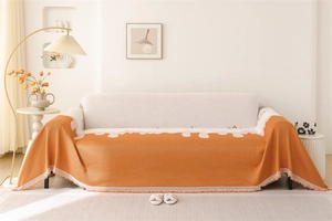 Close-up of Nordic orange chenille sofa cover with jacquard pattern and decorative fringe