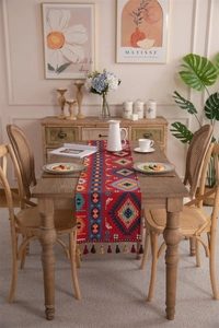 Detail of red Bohemian table runner with colorful geometric patterns and cotton tassels