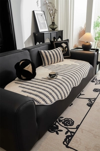 Detail of cream sofa cover with black wave patterns and scalloped edges on leather sofa