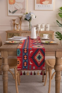 Macro detail of Bohemian woven table runner with red geometric patterns and fringe