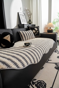 Detailed close-up of textured herringbone pattern sofa cushion on a black leather couch
