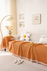 Detail of Nordic chenille sofa throw featuring orange geometric patterns and tassel edges
