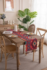 Detail of red woven table runner with geometric jacquard pattern and colorful tassels