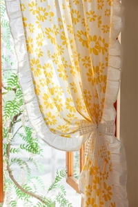 Detail of floral printed cotton curtain featuring ruffles and a white lace bow tie
