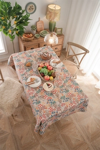 Detailaufnahme der Blumen-Jacquard-Tischdecke mit Fransen auf einem Holztisch bei Licht