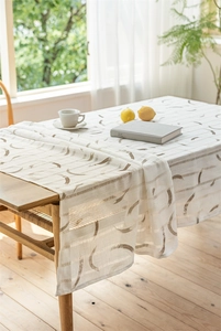 Detail der Jacquard-Tischdecke mit geometrischen Mustern und Fransen auf Holztisch