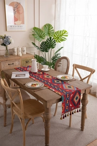 Detail of bohemian red table runner with geometric woven patterns and brown tassels