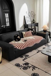 Detail of premium striped jacquard sofa cover with fringe edges on leather seating