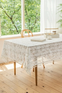 Detaillierte Ansicht der beigen Jacquard-Tischdecke mit elegantem Fransenbesatz auf einem Tisch