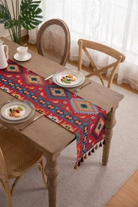 Close-up of bohemian red table runner with ethnic geometric patterns and brown tassels