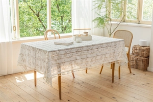 Detail der cremefarbenen rechteckigen Tischdecke mit Blumenmuster und feiner Fransenkante