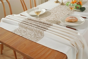 Gros plan d'un chemin de table nordique montrant la texture tissée beige et les motifs de feuilles