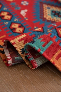 Macro detail of geometric jacquard fabric with tassels on rustic wooden table surface
