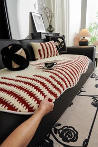 Close-up of wavy striped plush sofa cover in cream and red with textured soft fabric