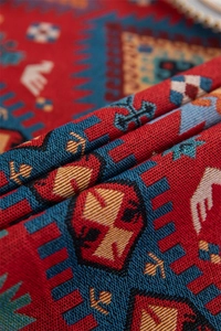 Macro shot of red jacquard fabric with vintage floral patterns and fringe details